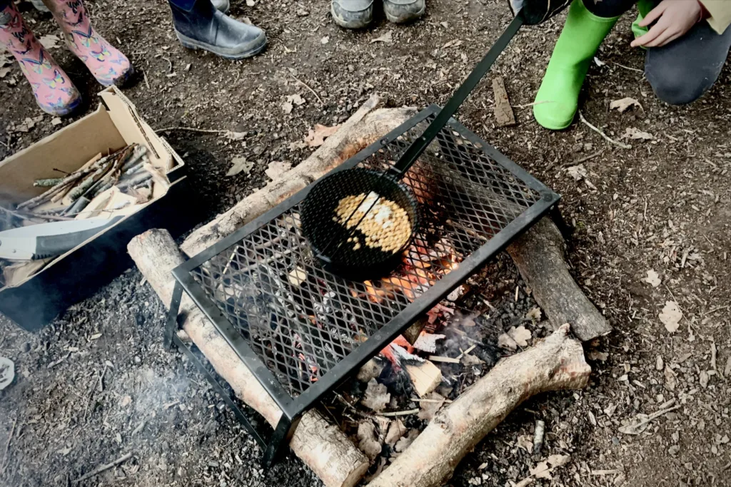 Campfire popcorn toasting over an open fire.